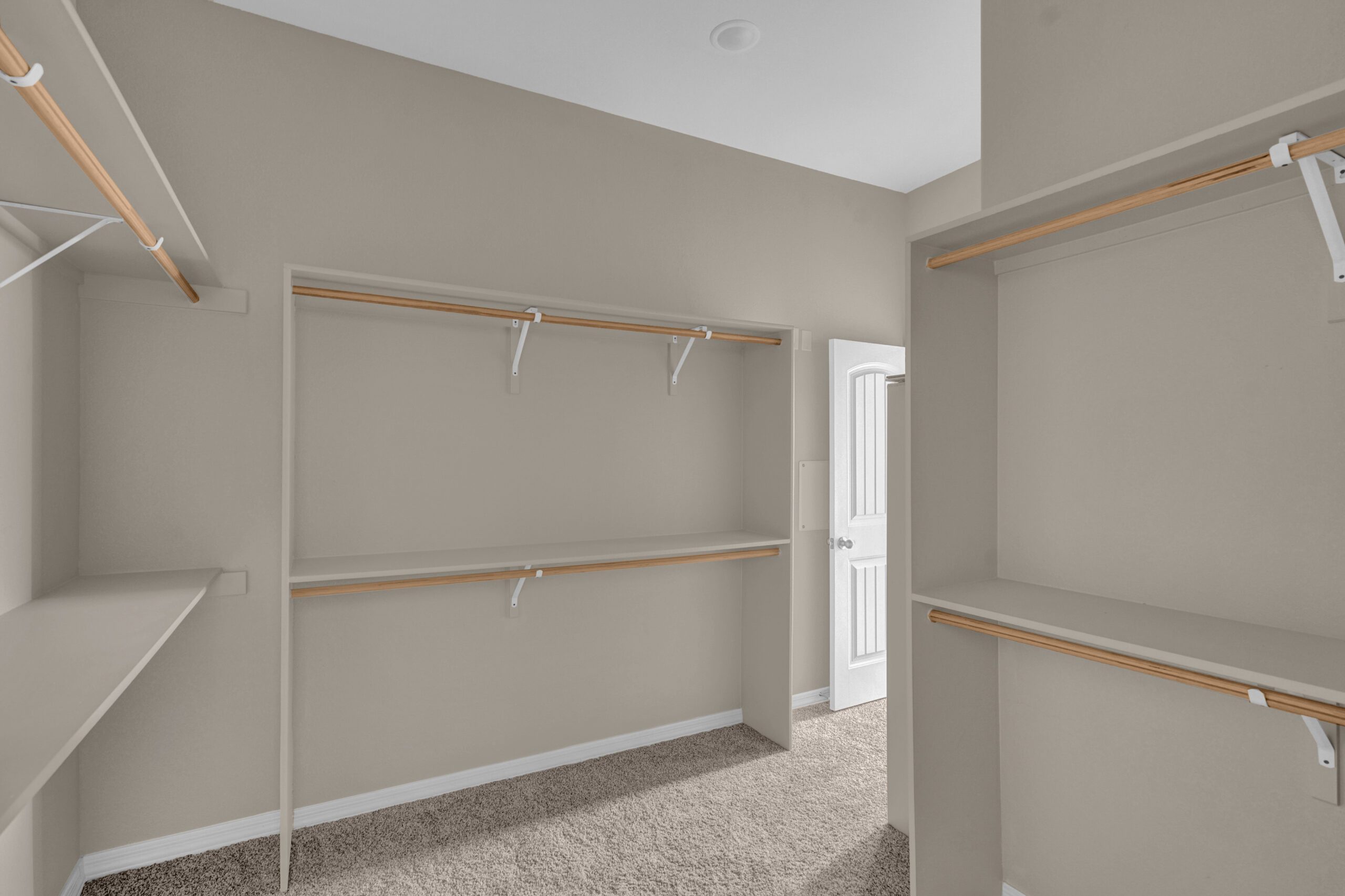 Spacious walk-in closet with built-in shelves and hanging rods in The Paprika model