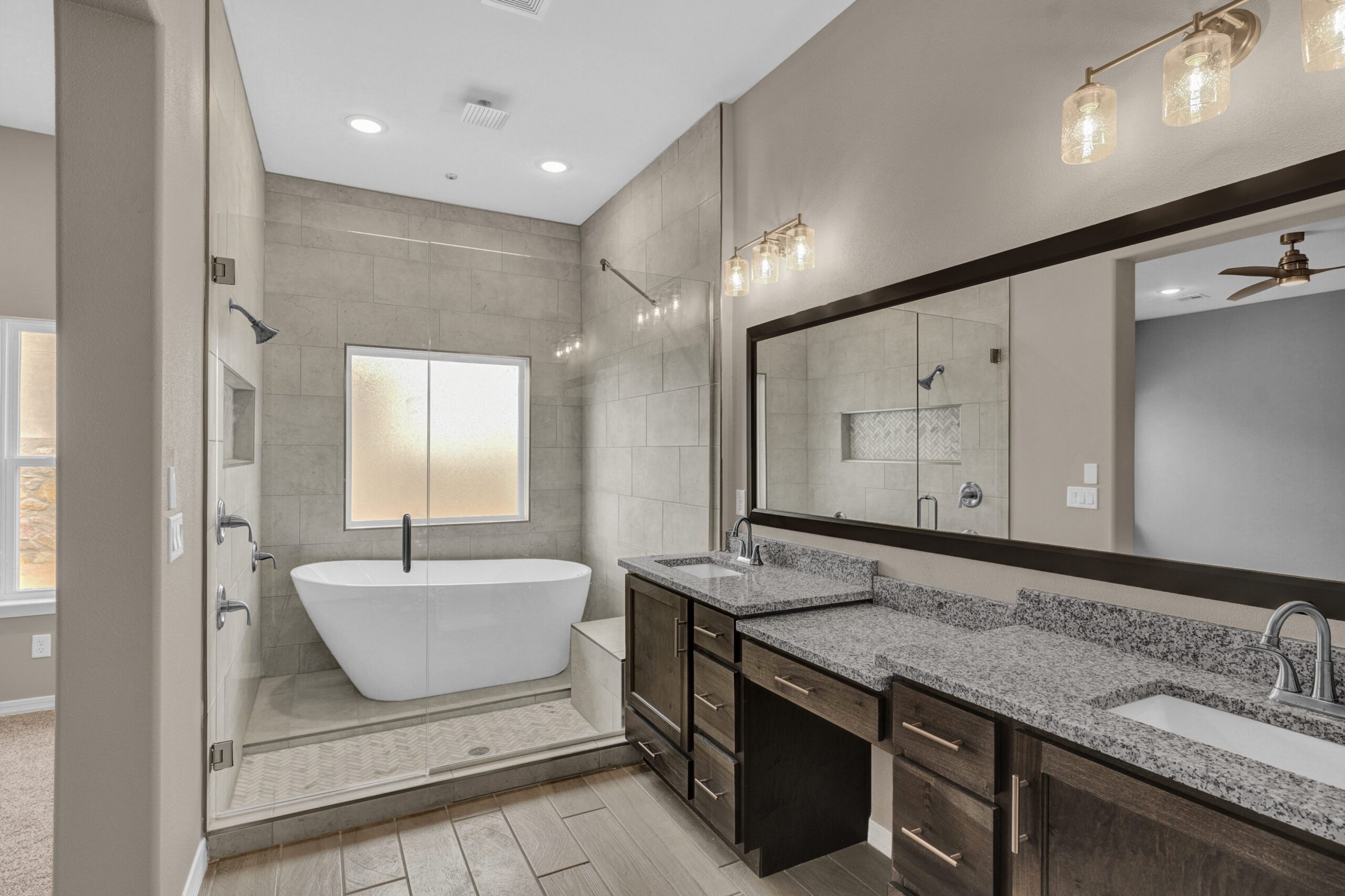 Primary bathroom in The Paprika model featuring walk-in shower, freestanding tub, and dual vanities