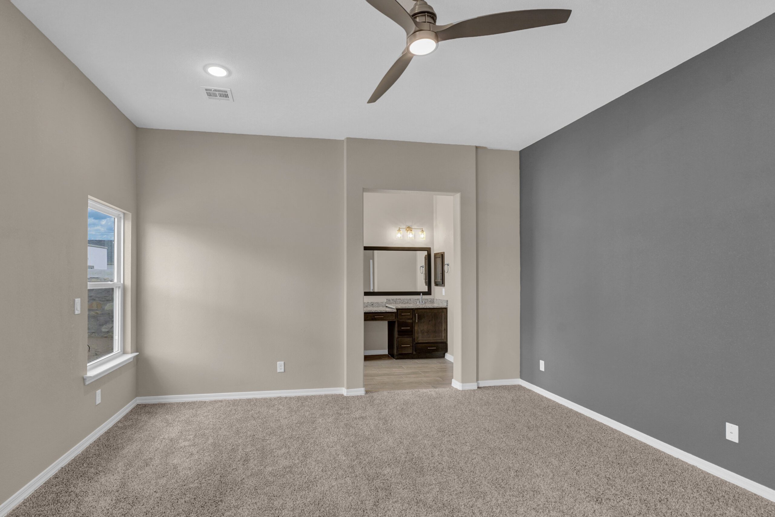 Primary bedroom in The Paprika model with neutral walls, gray accent, and en suite bathroom