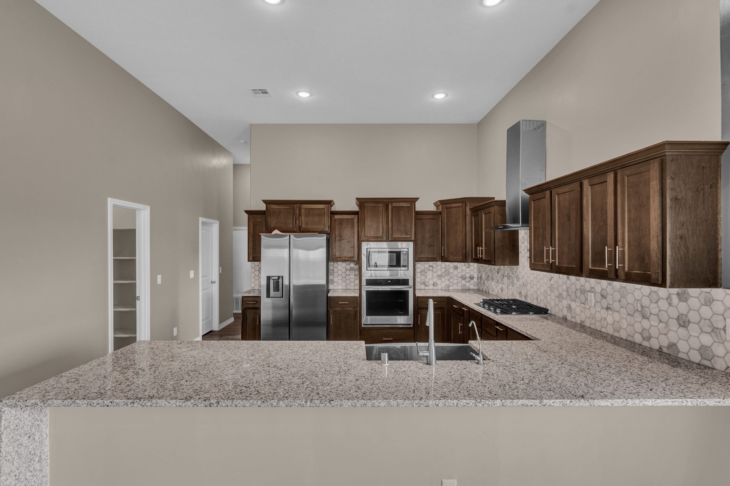 Close-up view of The Paprika kitchen featuring granite countertops, dark wood cabinets, and stainless steel appliances