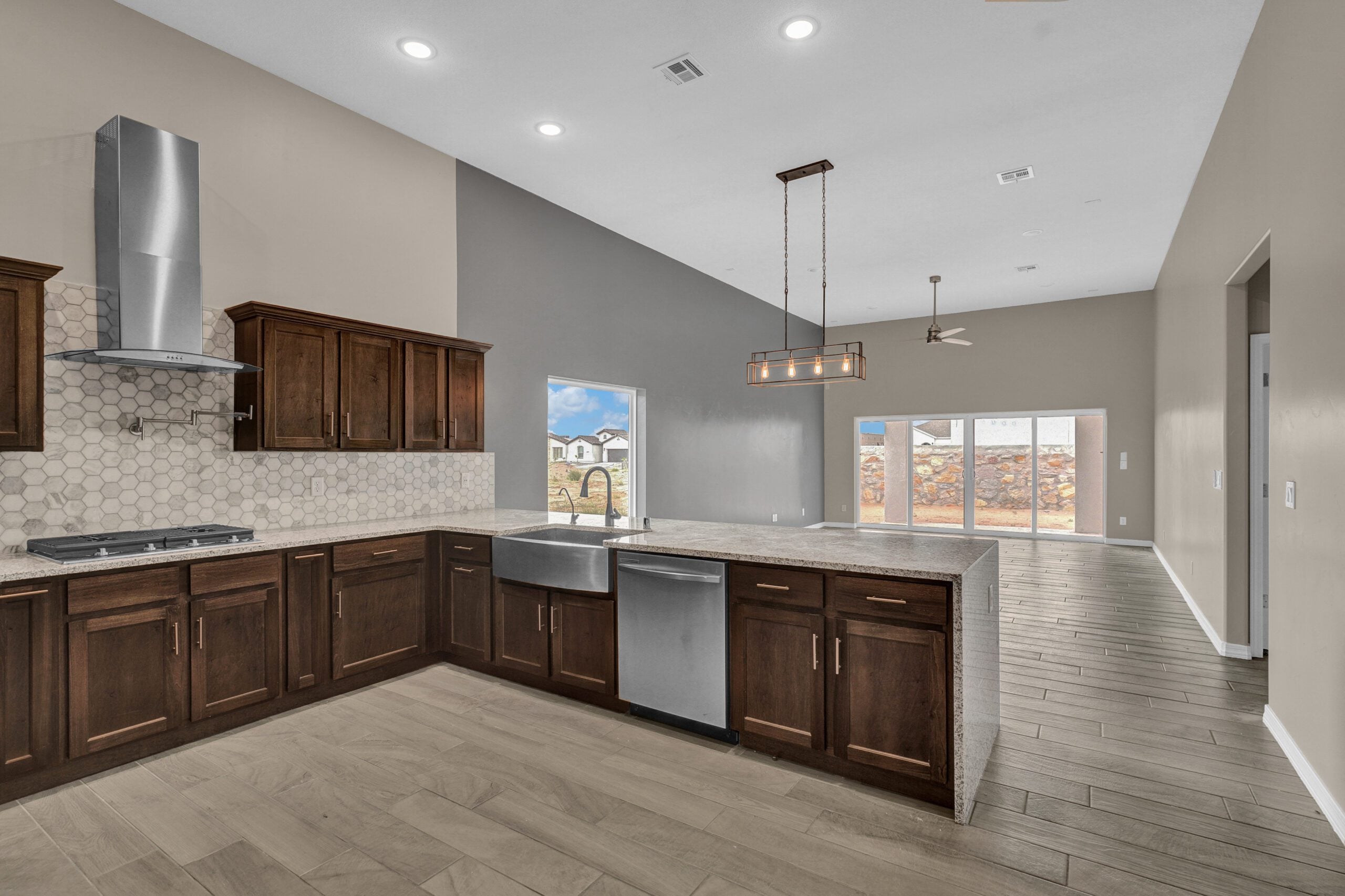 Modern kitchen and open living area in The Paprika floor plan featuring dark wood cabinets and large windows.
