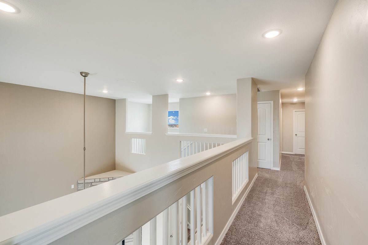 Upstairs hallway in The Chiffon with carpeted flooring, recessed lighting, and white railing overlooking the lower level.