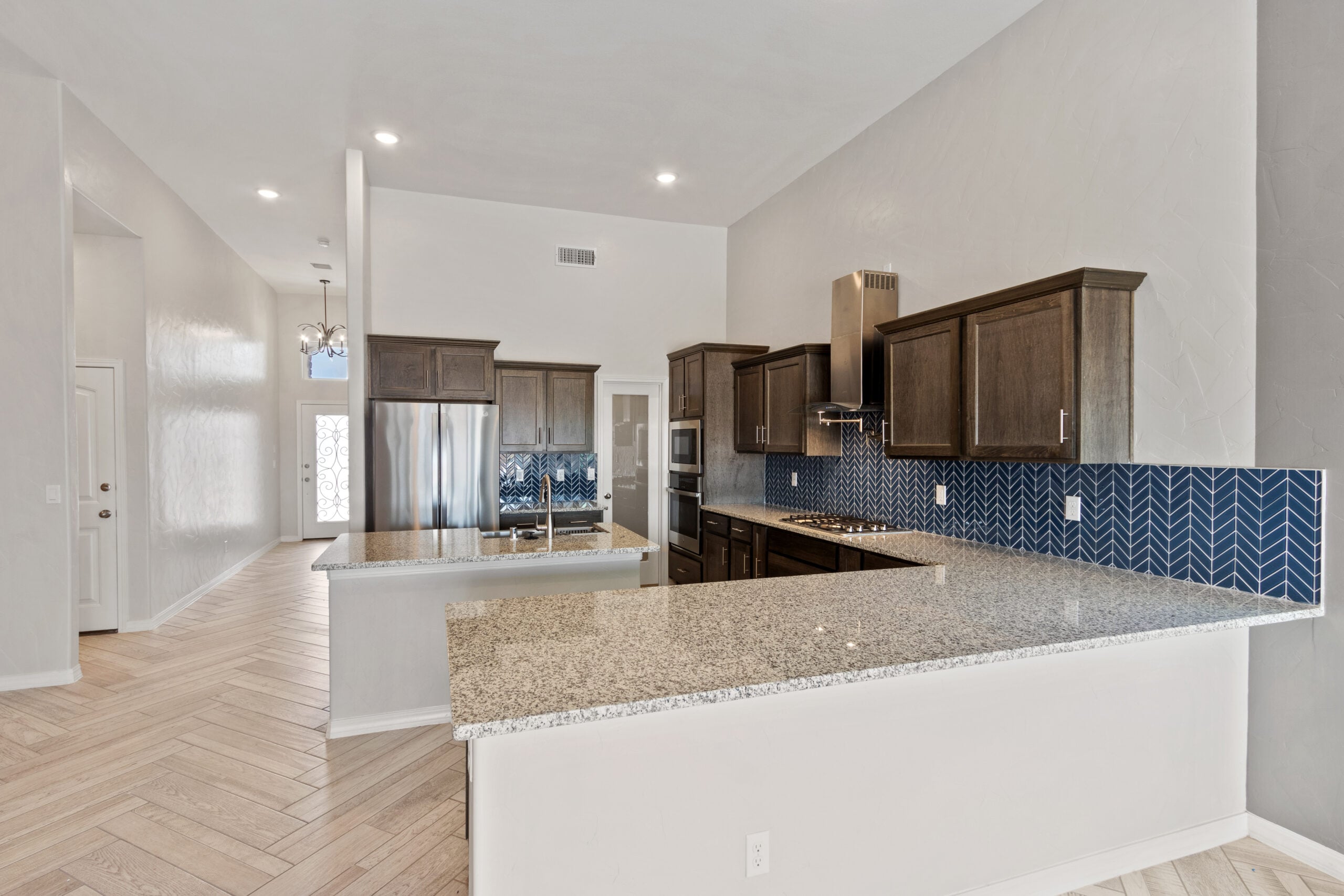 The Juniper kitchen featuring dark wood cabinetry, granite countertops, and a bold chevron tile backsplash.