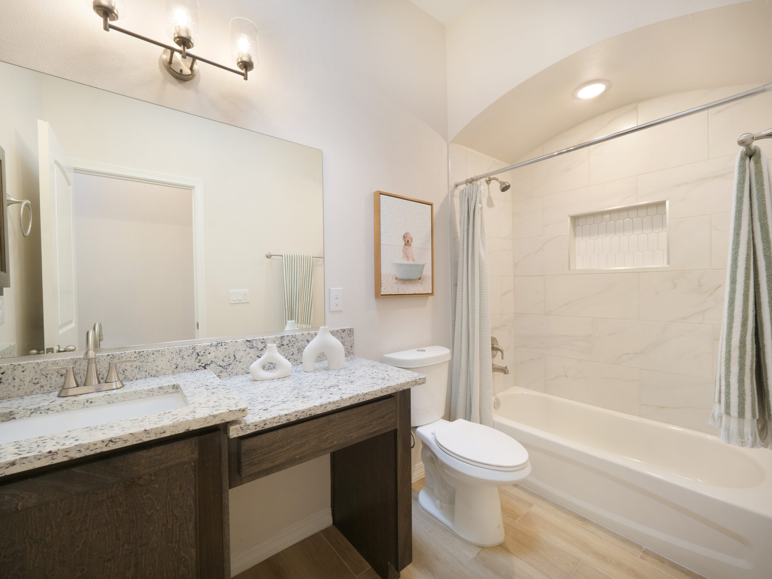 Secondary bathroom in The Rose model by Zia Homes with granite vanity, built-in bathtub, and modern lighting.
