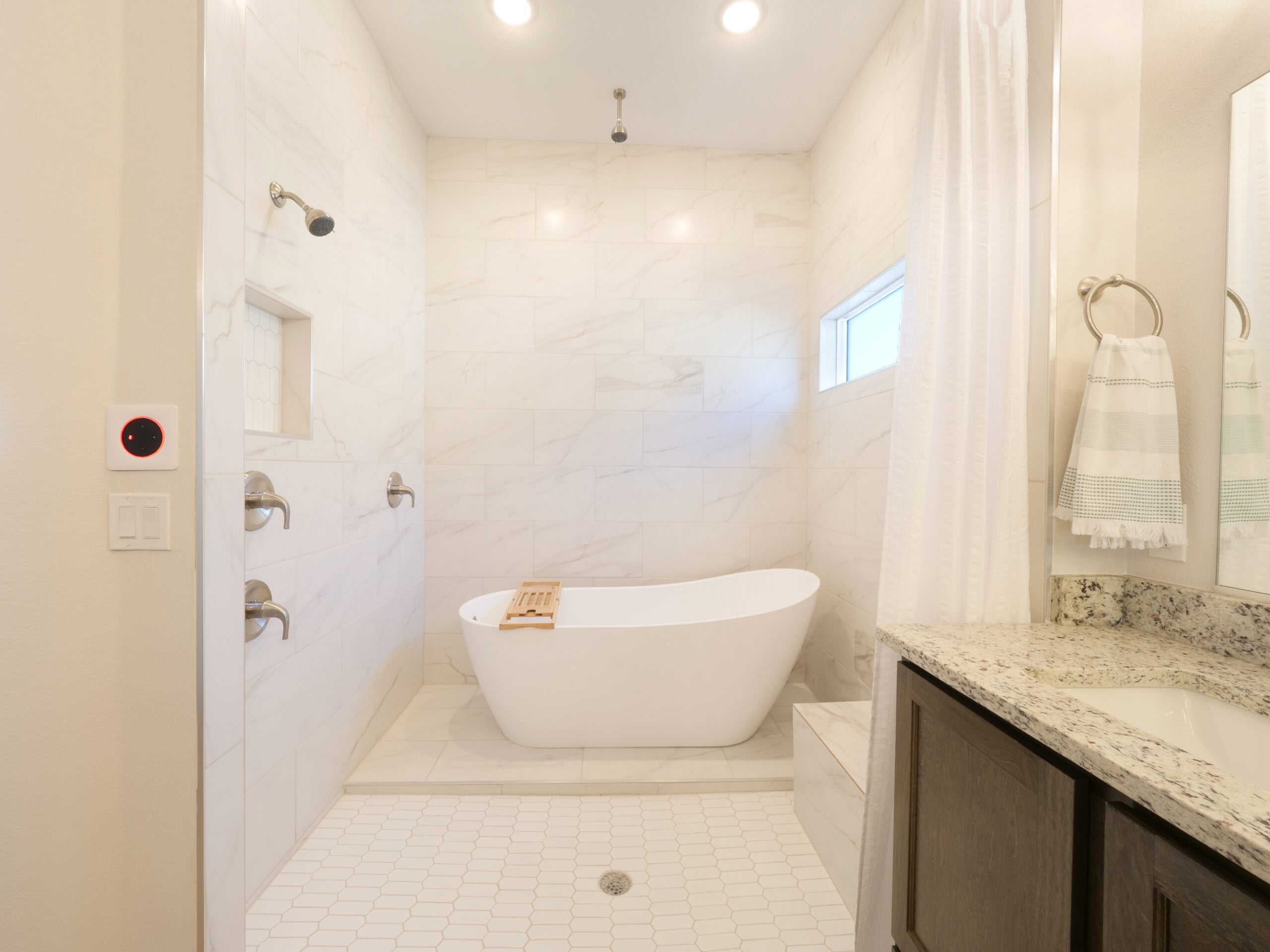 Luxurious spa-style bathroom in The Rose model by Zia Homes with a freestanding tub, double shower heads, and granite countertop vanity.