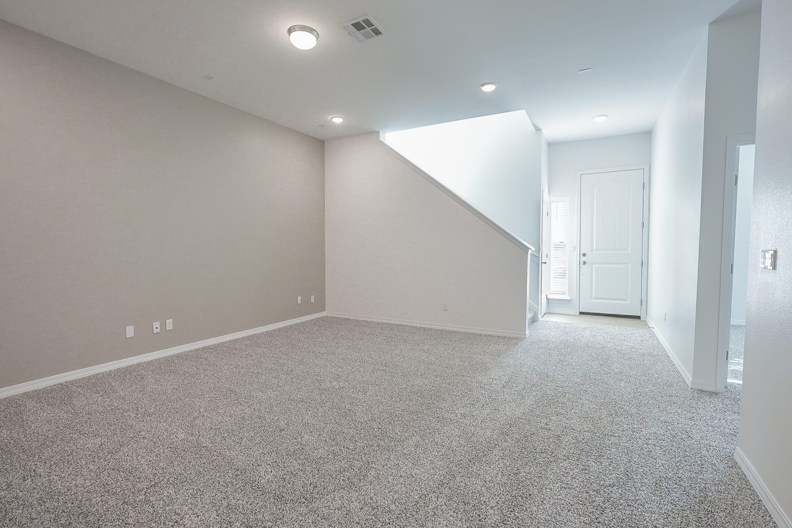 Open flex space in The Playa home by Zia Homes with neutral carpeting, recessed lighting, and stairway access.