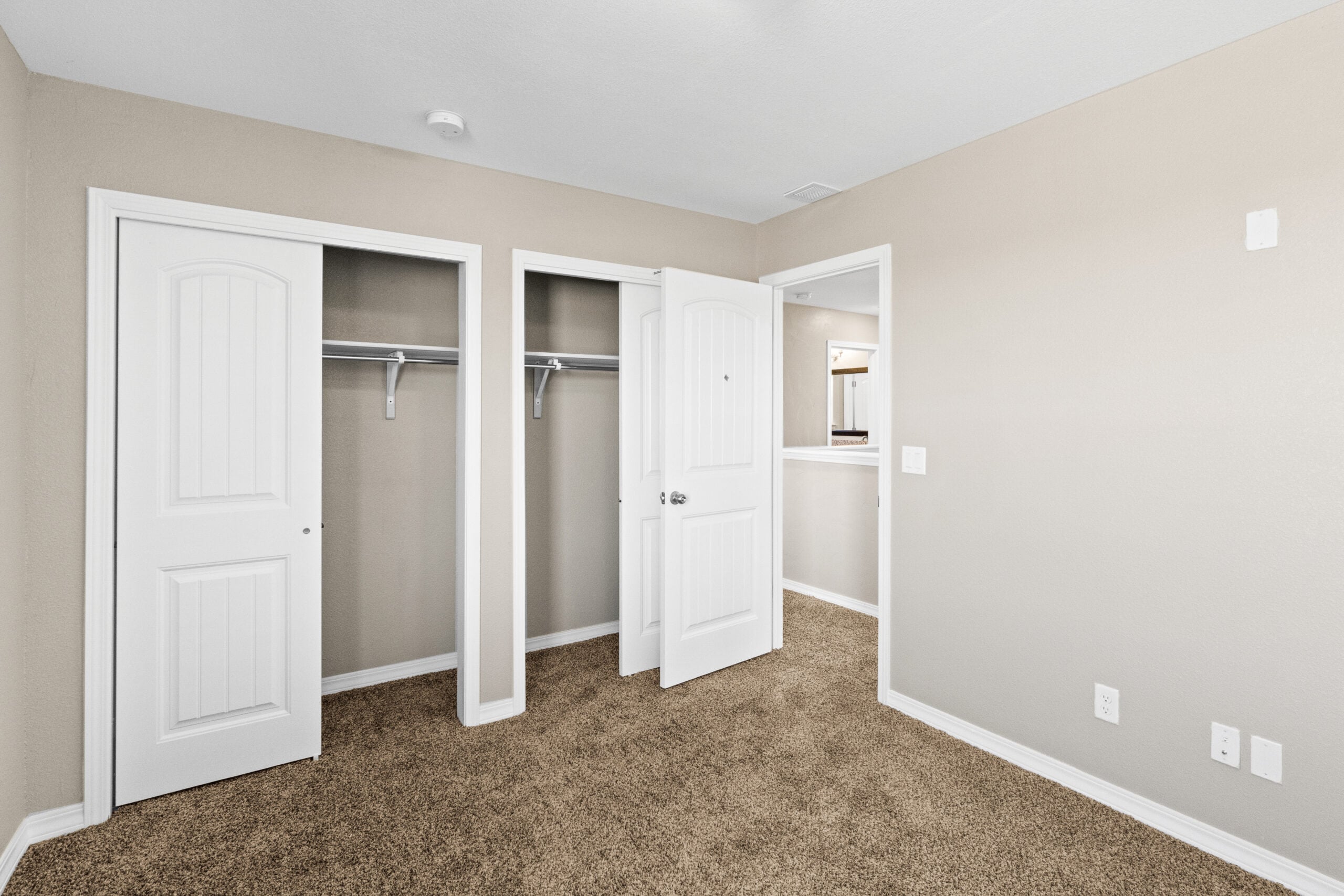 Bedroom view in The Trellis model featuring dual closets and neutral-tone finishes.