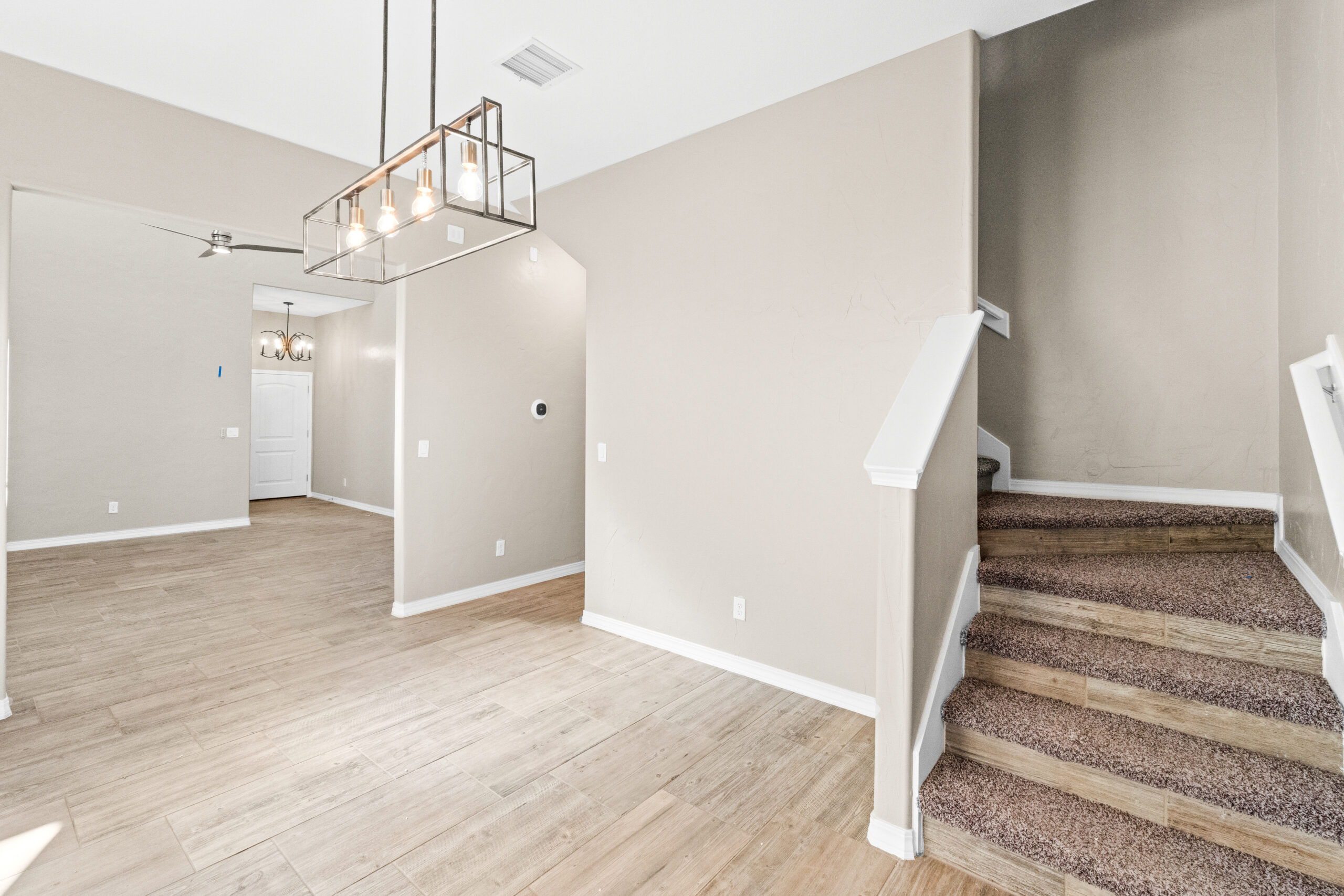 Interior view of The Trellis entryway and staircase with modern chandelier and light wood flooring.