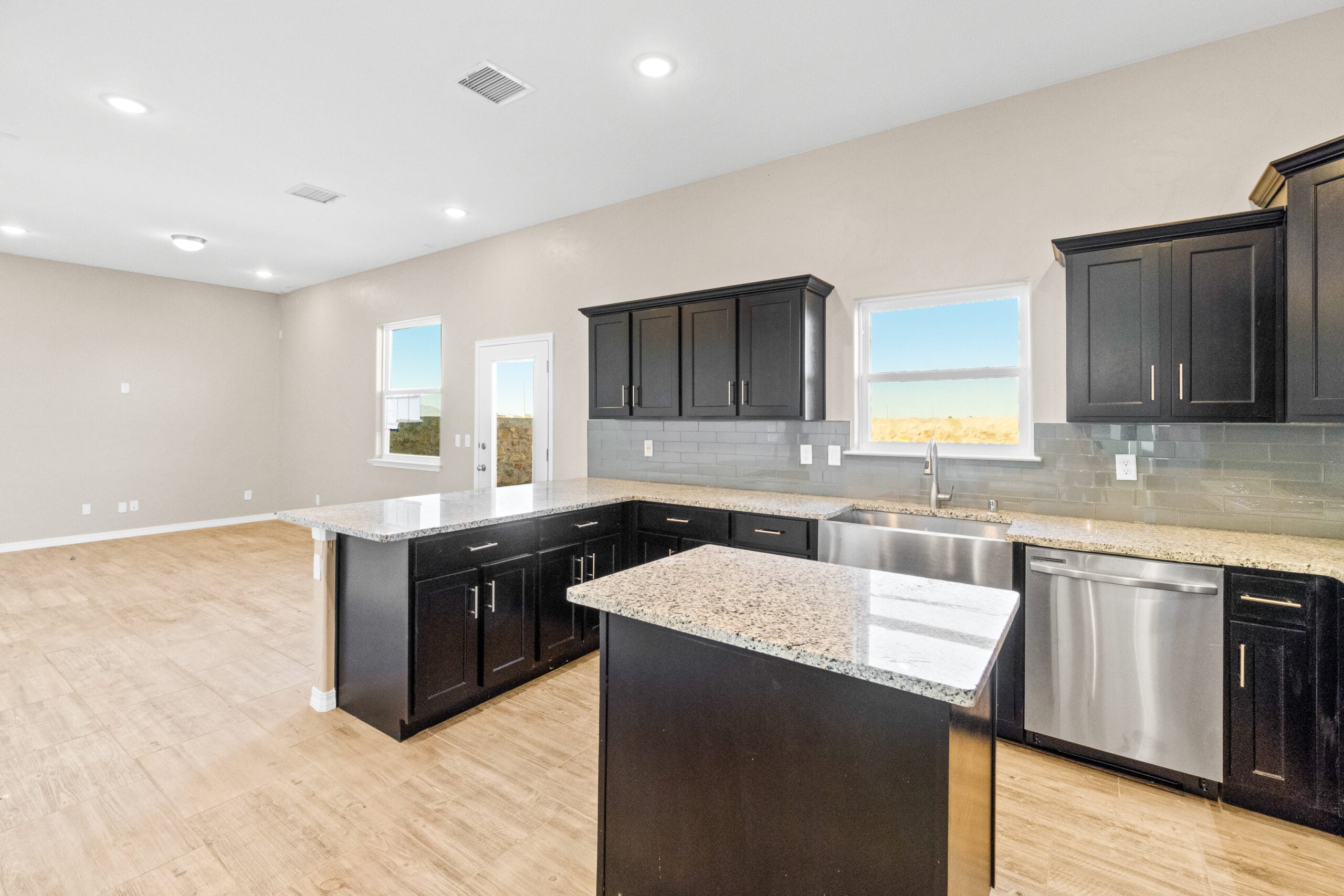Wide-angle view of The Trellis kitchen featuring dark cabinets, granite countertops, and stainless steel appliances.