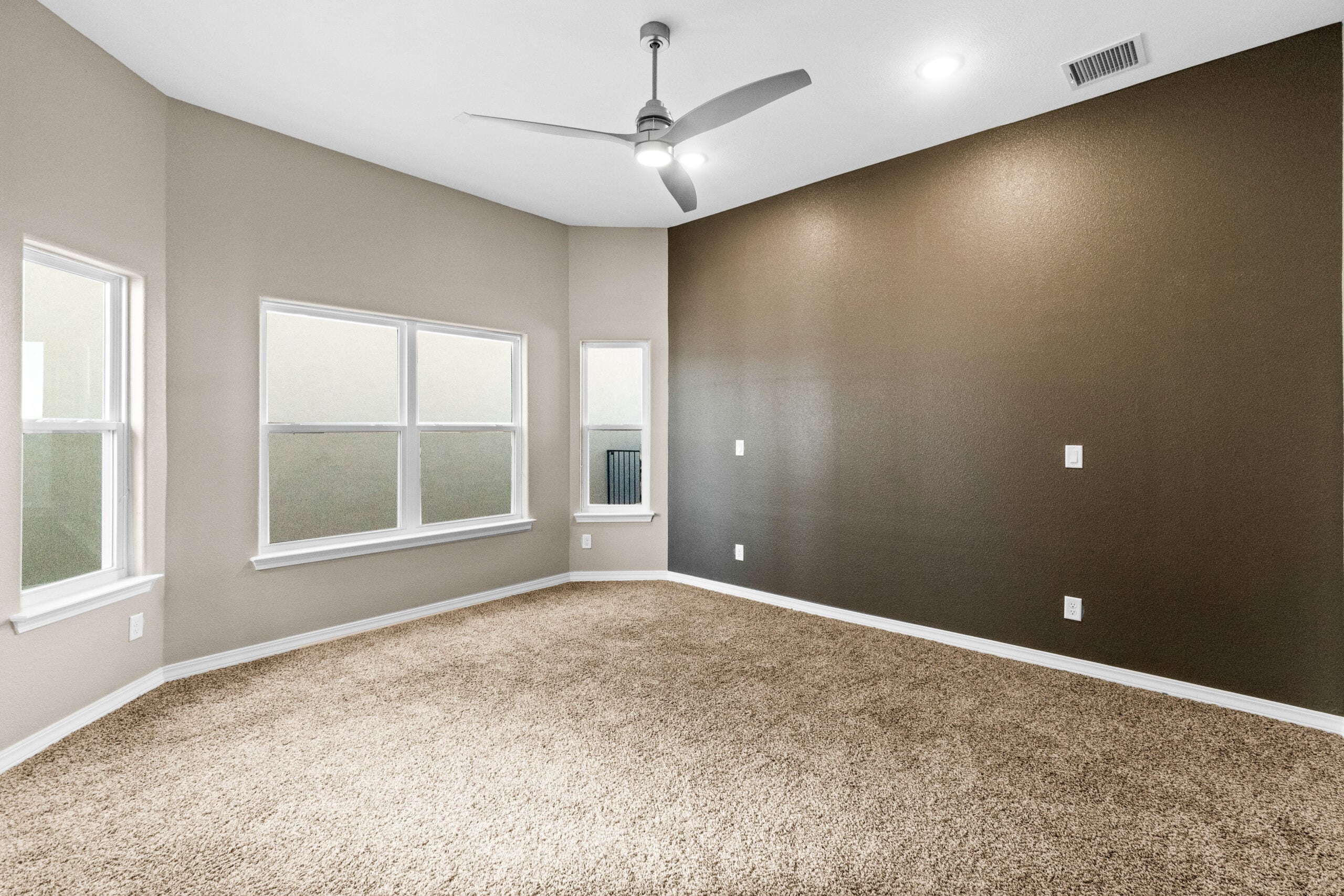 Spacious carpeted bedroom in The Trellis model with accent wall and natural lighting.