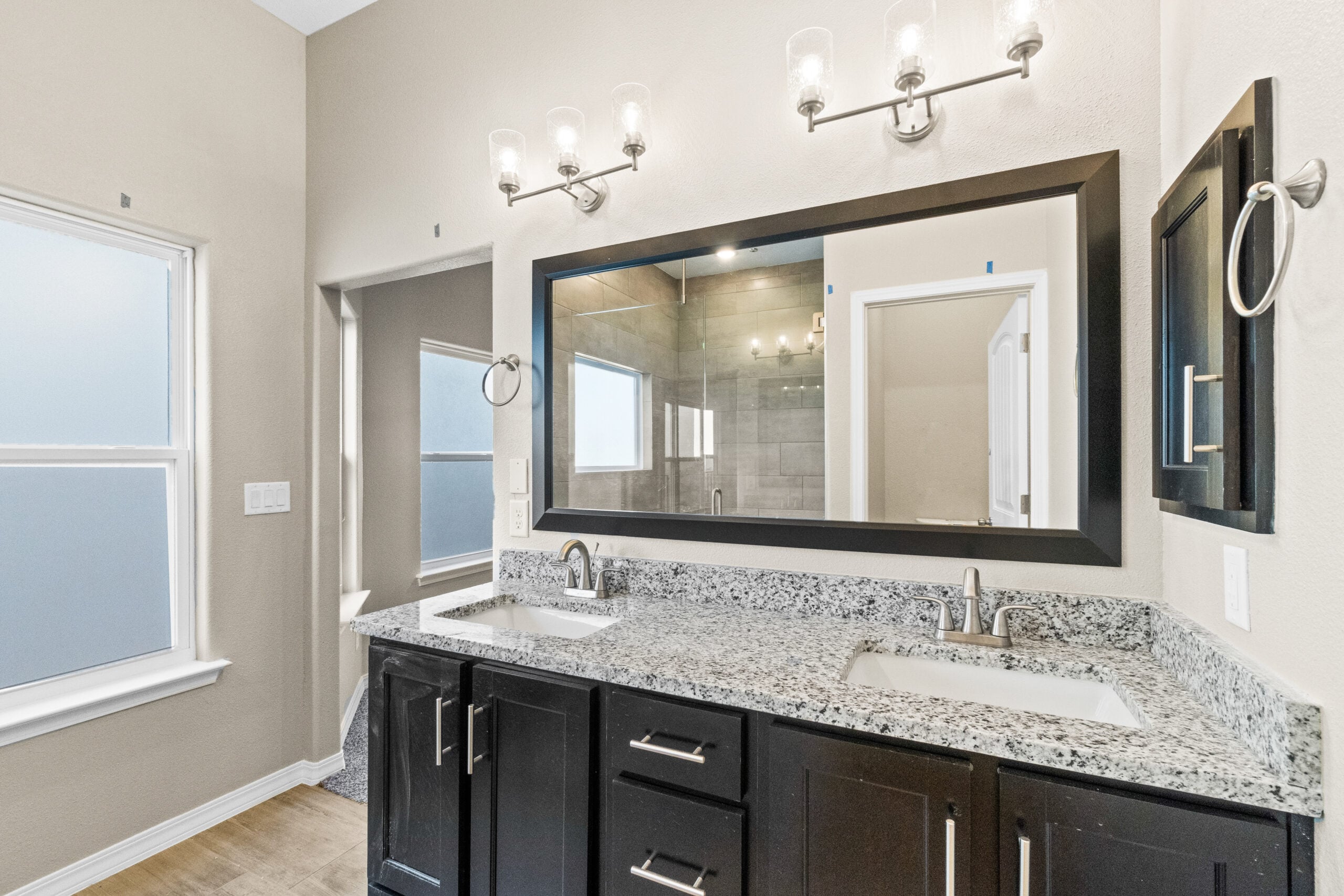 Double-sink bathroom vanity with granite countertops and modern lighting in The Trellis model by Zia Homes.