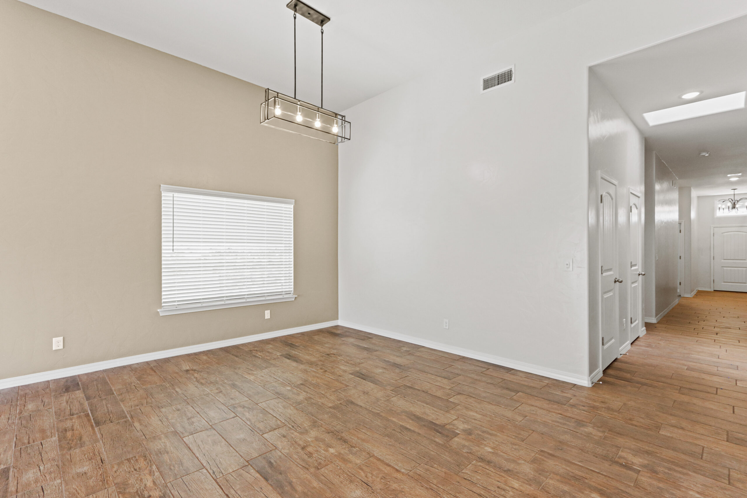 Open dining space in The Organza with wood-look tile flooring and a modern chandelier.