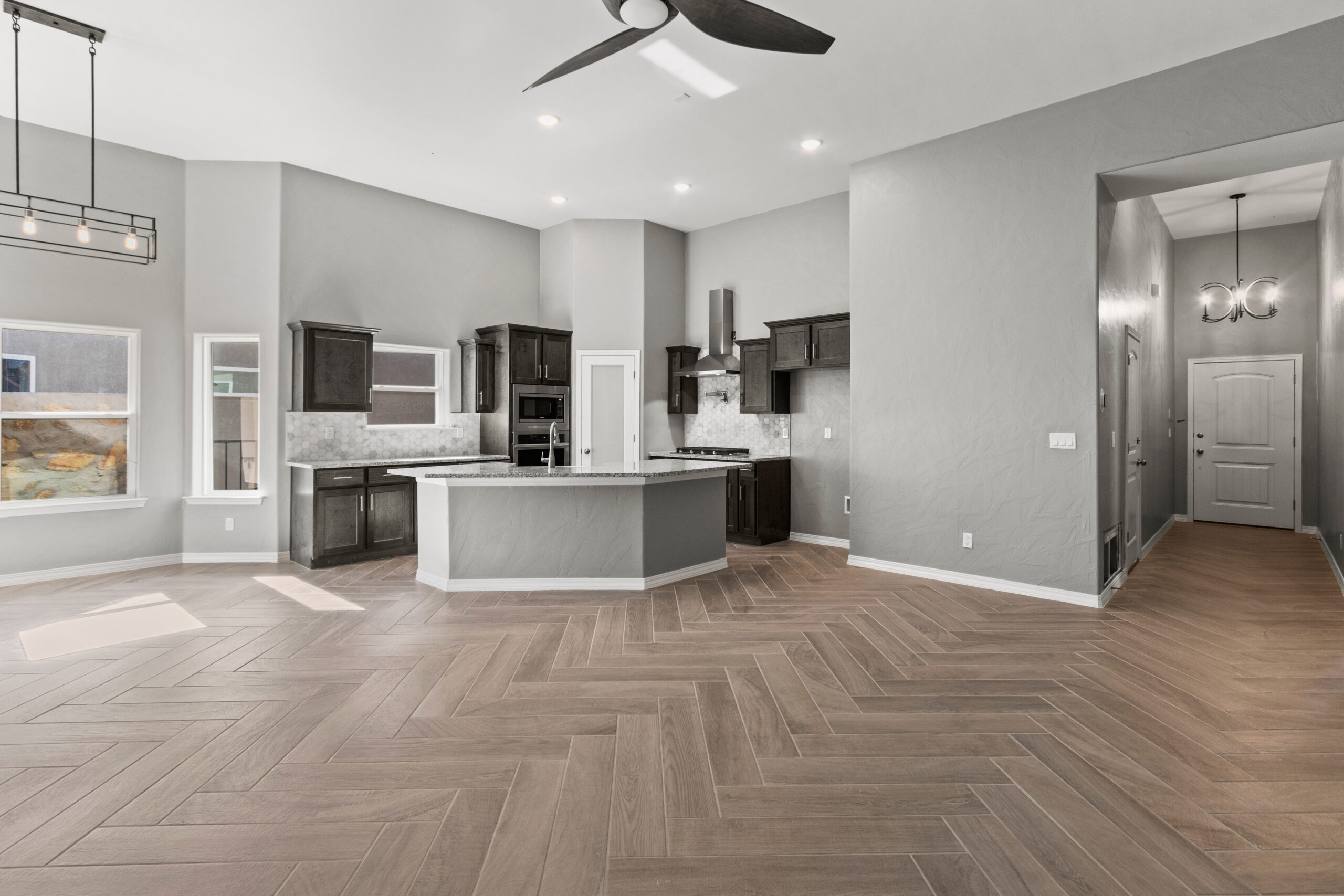 Open concept kitchen and entryway of The Poplin model with modern lighting and herringbone tile floors