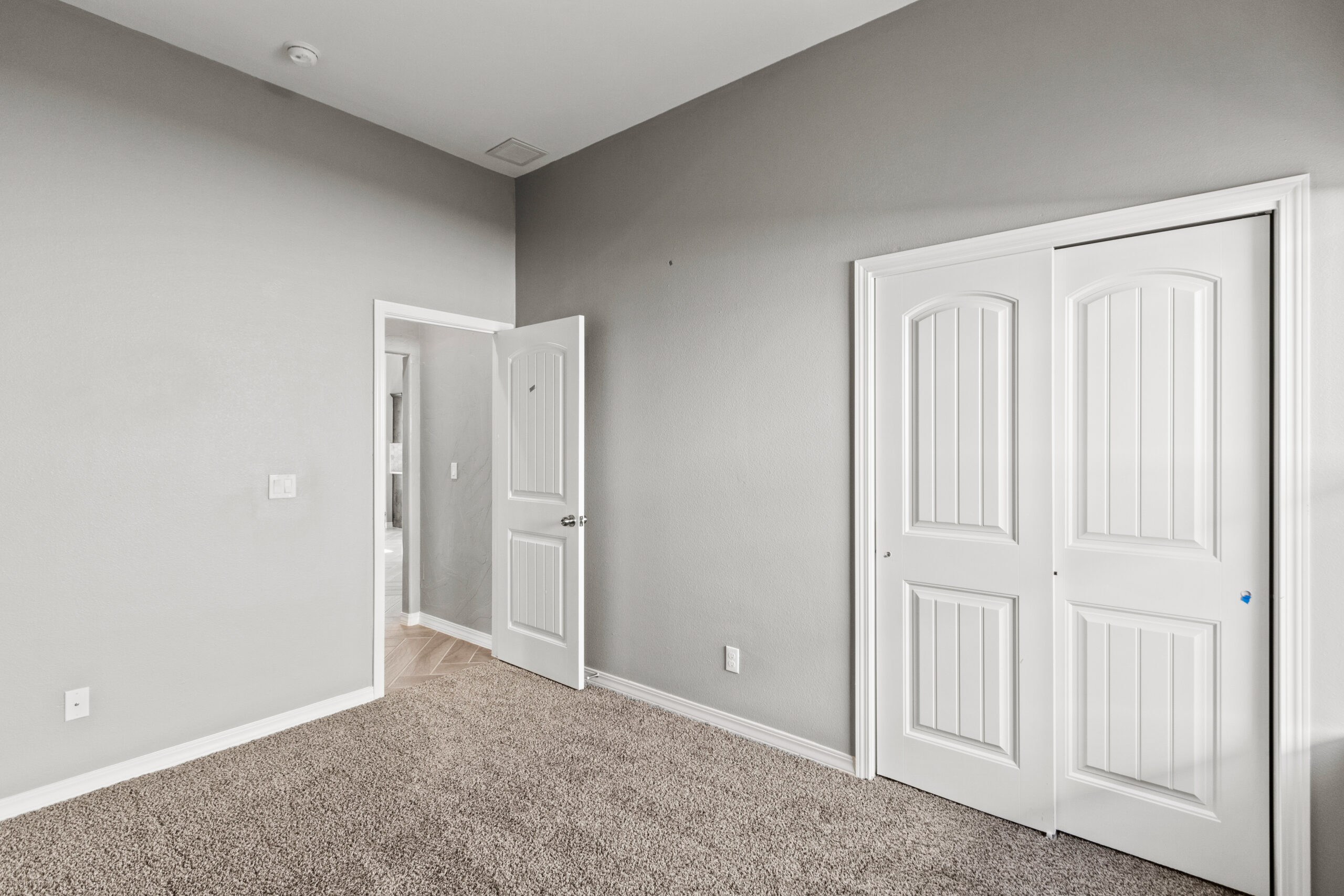Primary bedroom in The Poplin model with carpet flooring, closet with double doors, and hallway access
