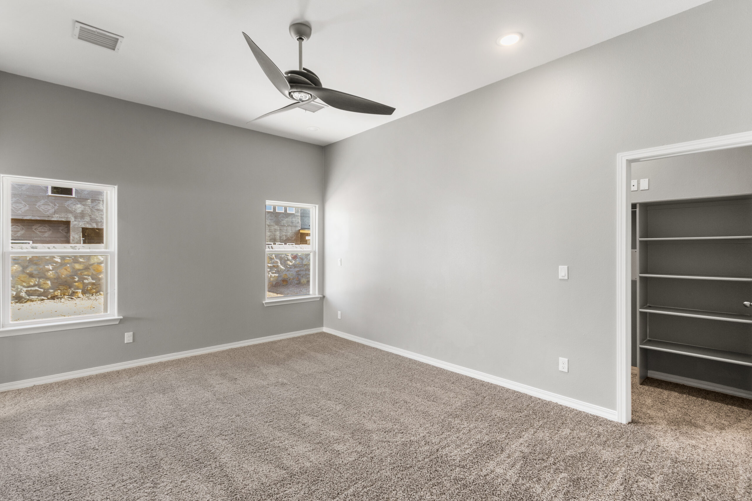 Primary bedroom in The Poplin model featuring plush carpet, ceiling fan, and walk-in closet access