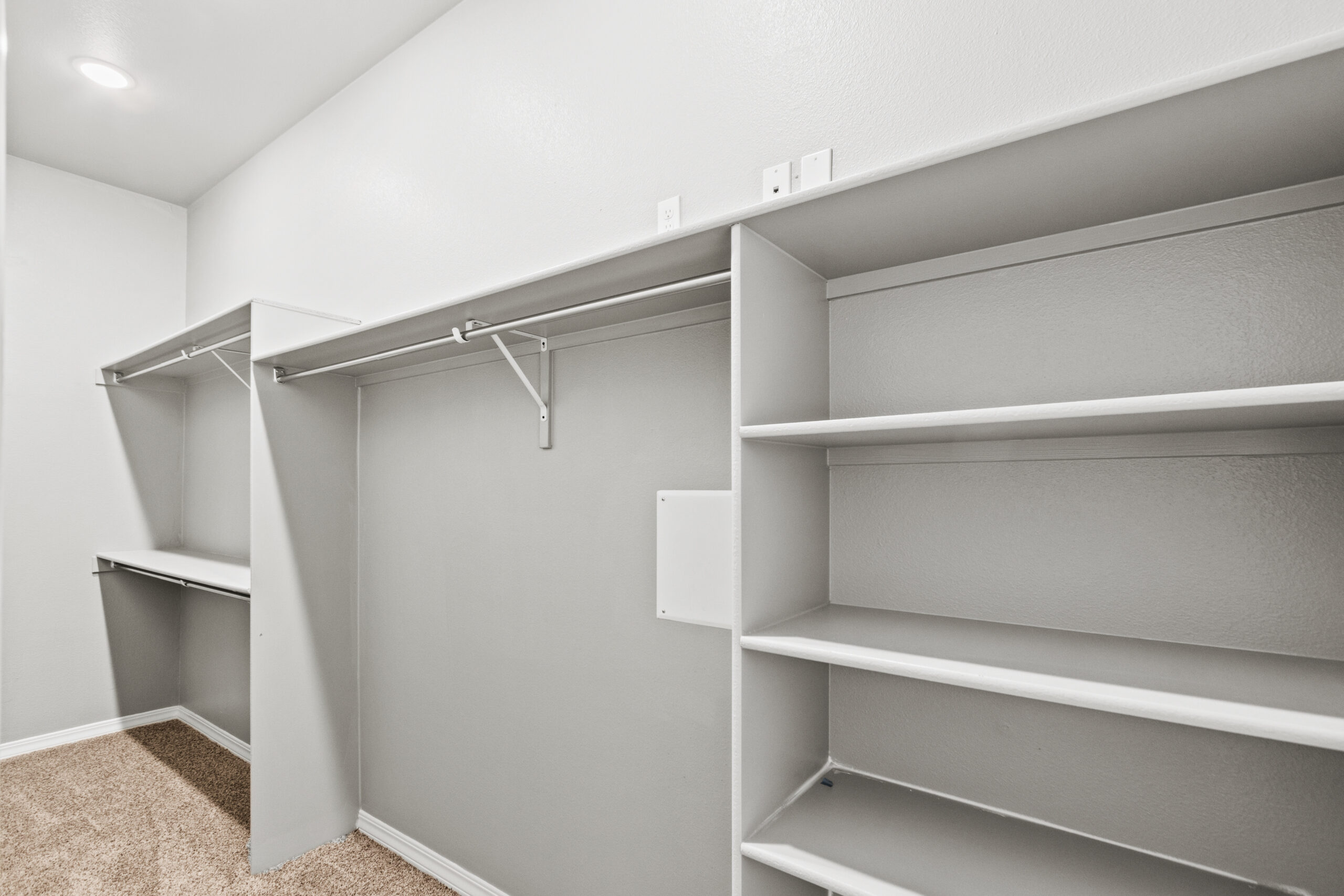 Spacious walk-in closet in The Poplin model with built-in shelving and hanging rods