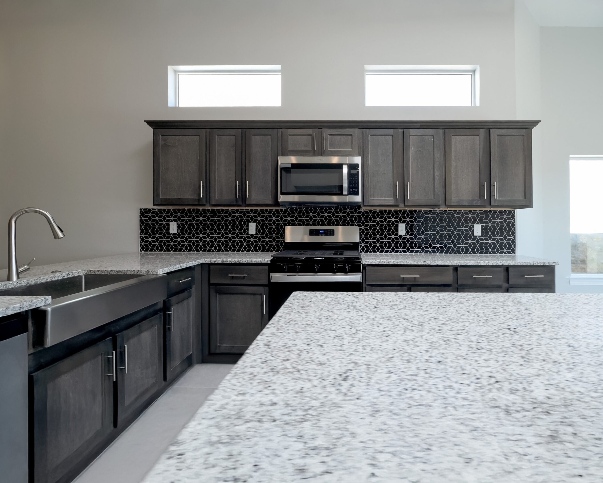 The Lotus large kitchen with a floating island, breakfast bar, and black tiled backsplash.