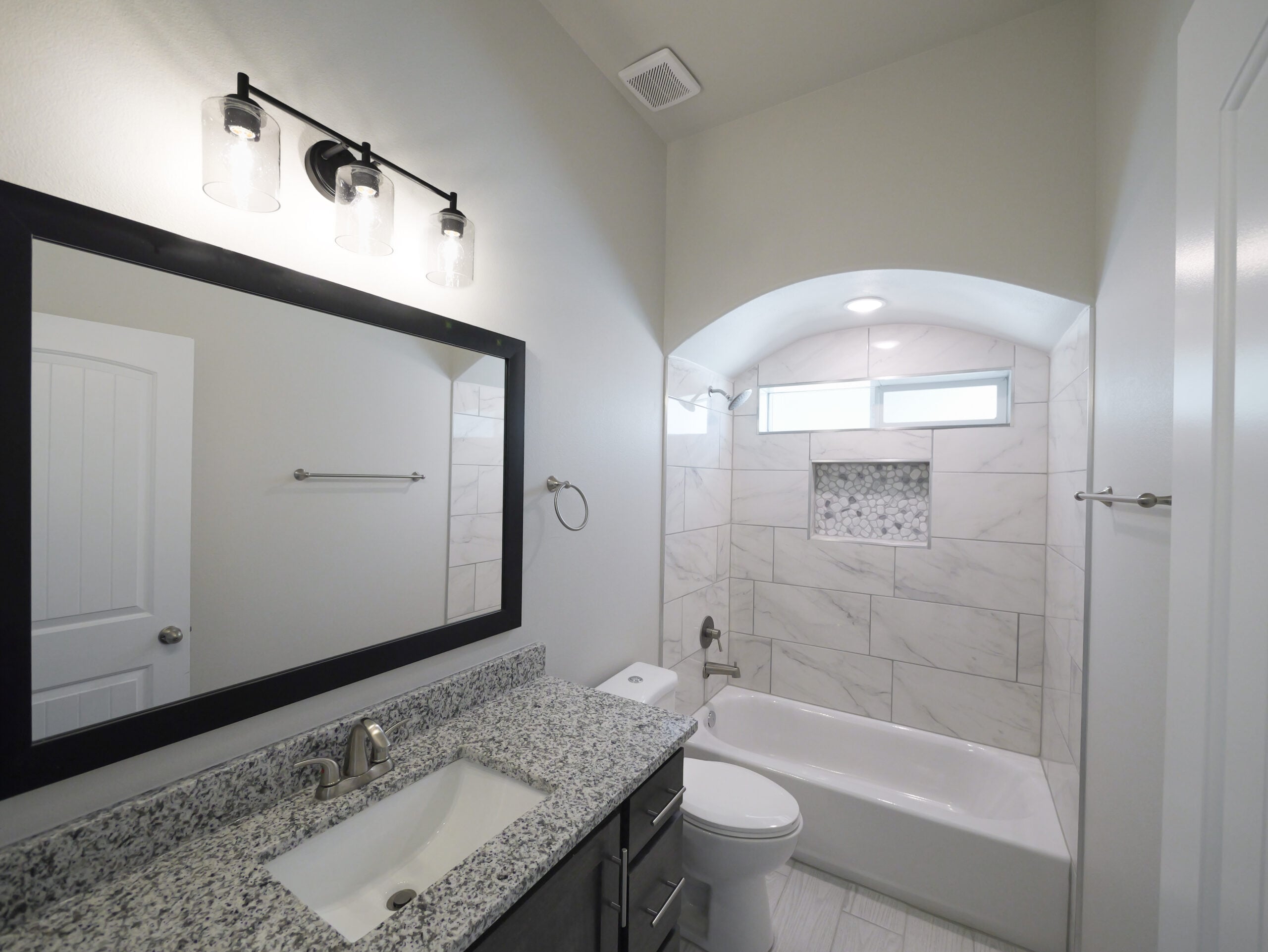 Hibiscus Bathroom with a large mirror, dark wood cabinets, and granite countertops. The shower has a window that allows plenty of natural lighting.