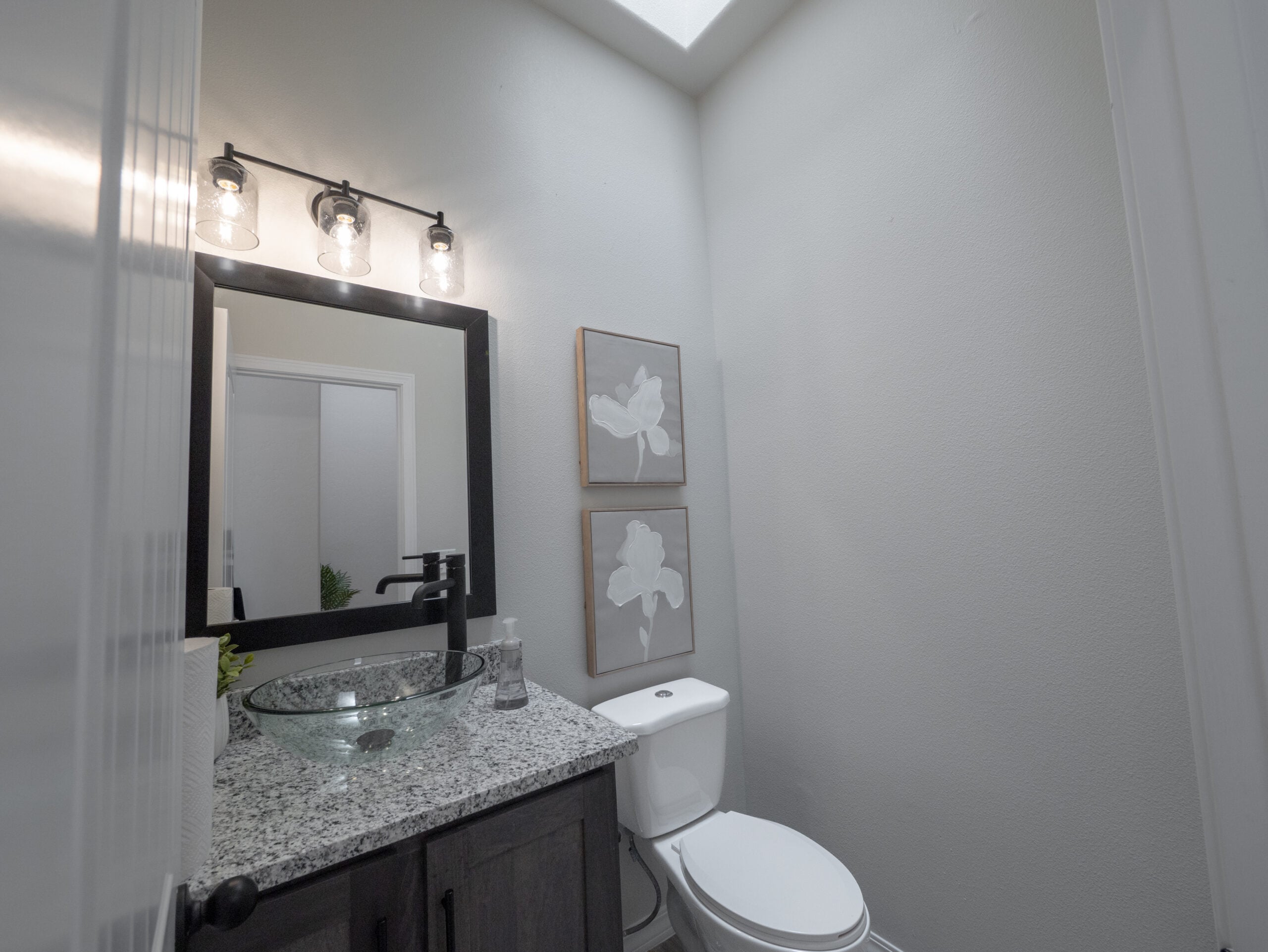 The Chai Bathroom with dark wood cabinets, stainless steel, and a skylgiht.