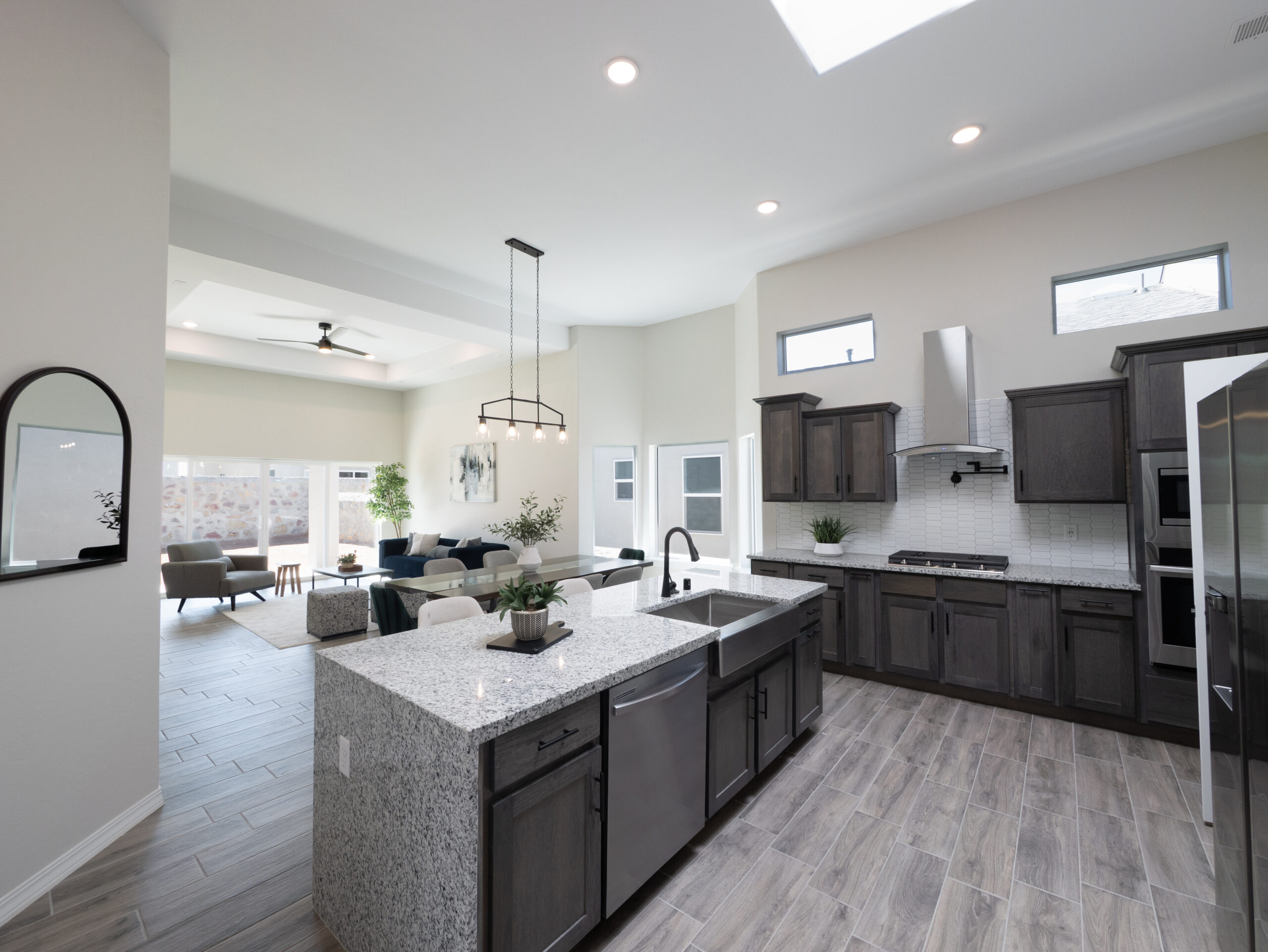 The Chai Kitchen with a skylight, dark wood cabinets, granite countertops, and black / stainless steel appliances.
