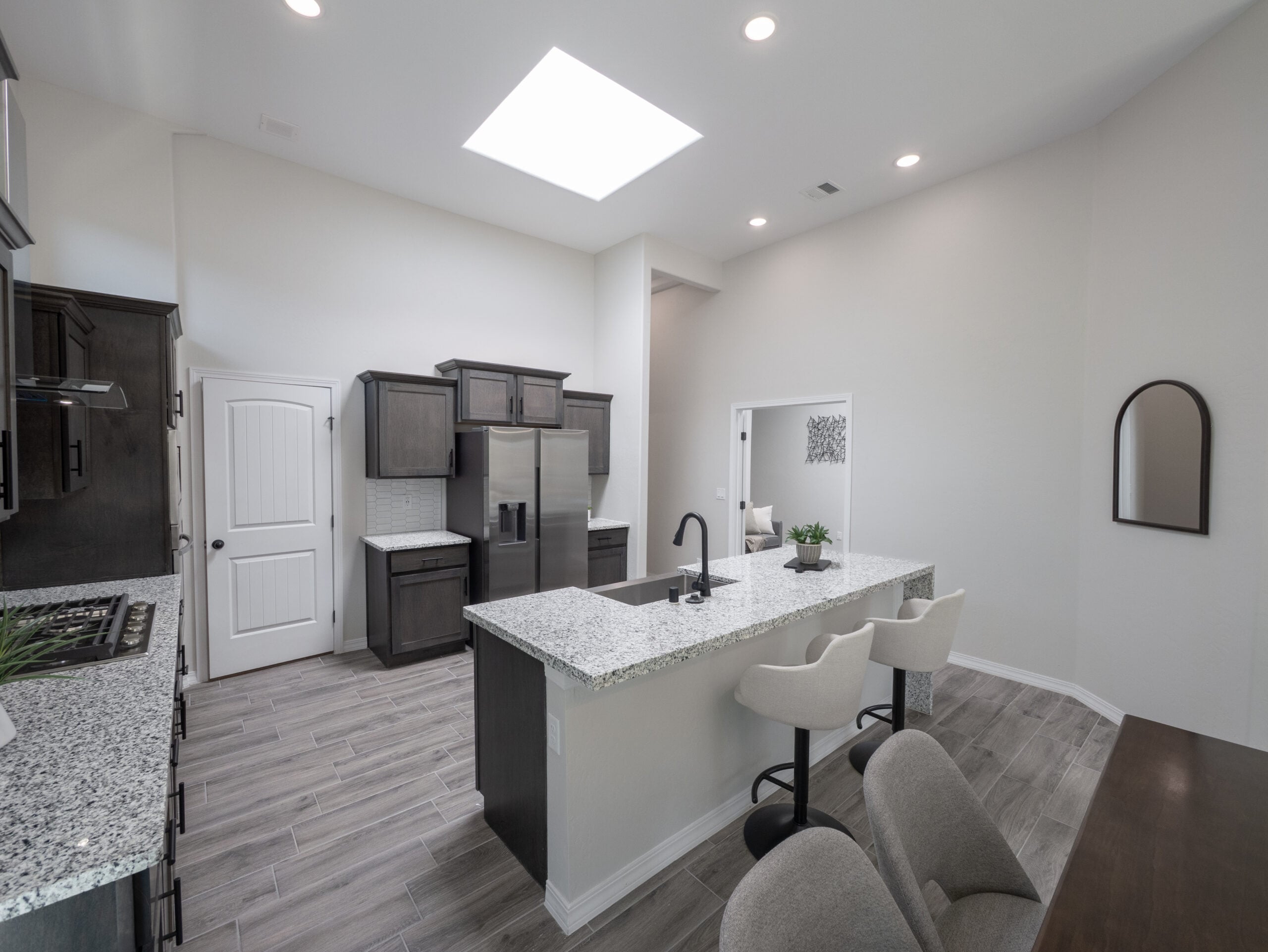 The Chai Kitchen with a skylight, dark wood cabinets, granite countertops, and black / stainless steel appliances.