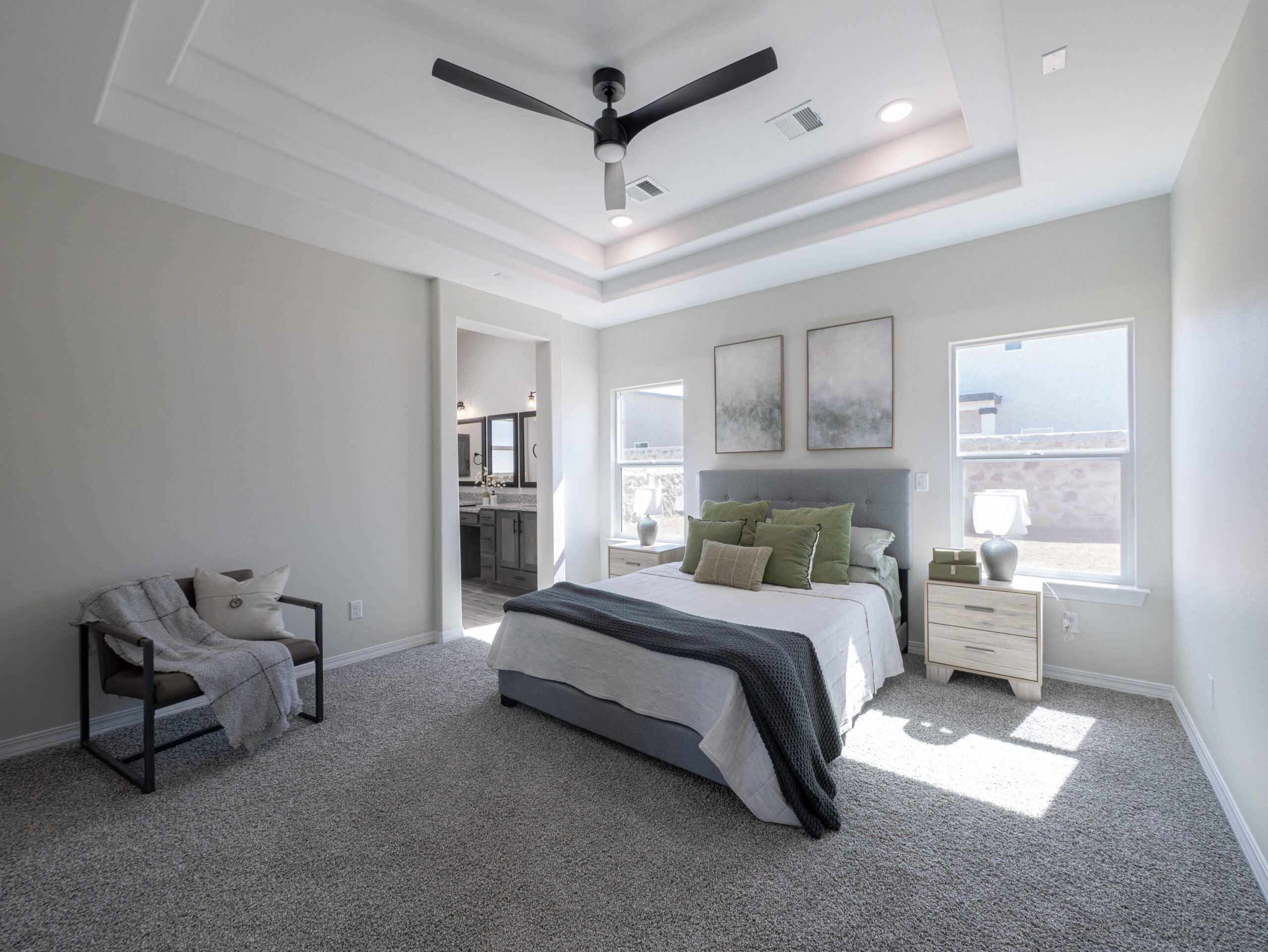 The Chai Master Bedroom with tray ceilings, a black fan, and two large windows that allow natural lighting.