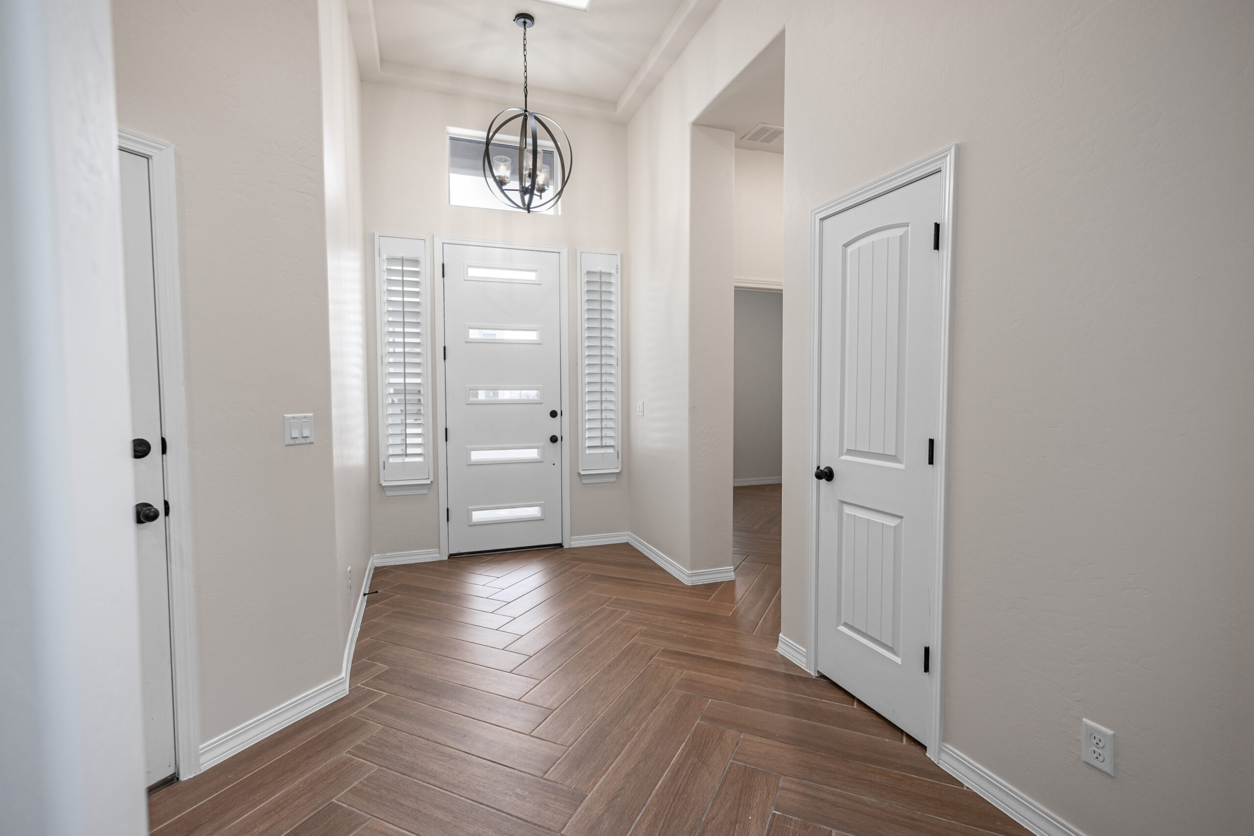The Daisy Entrance with a big front door and two windows and either side. There is a light fixture that is above the entrance.