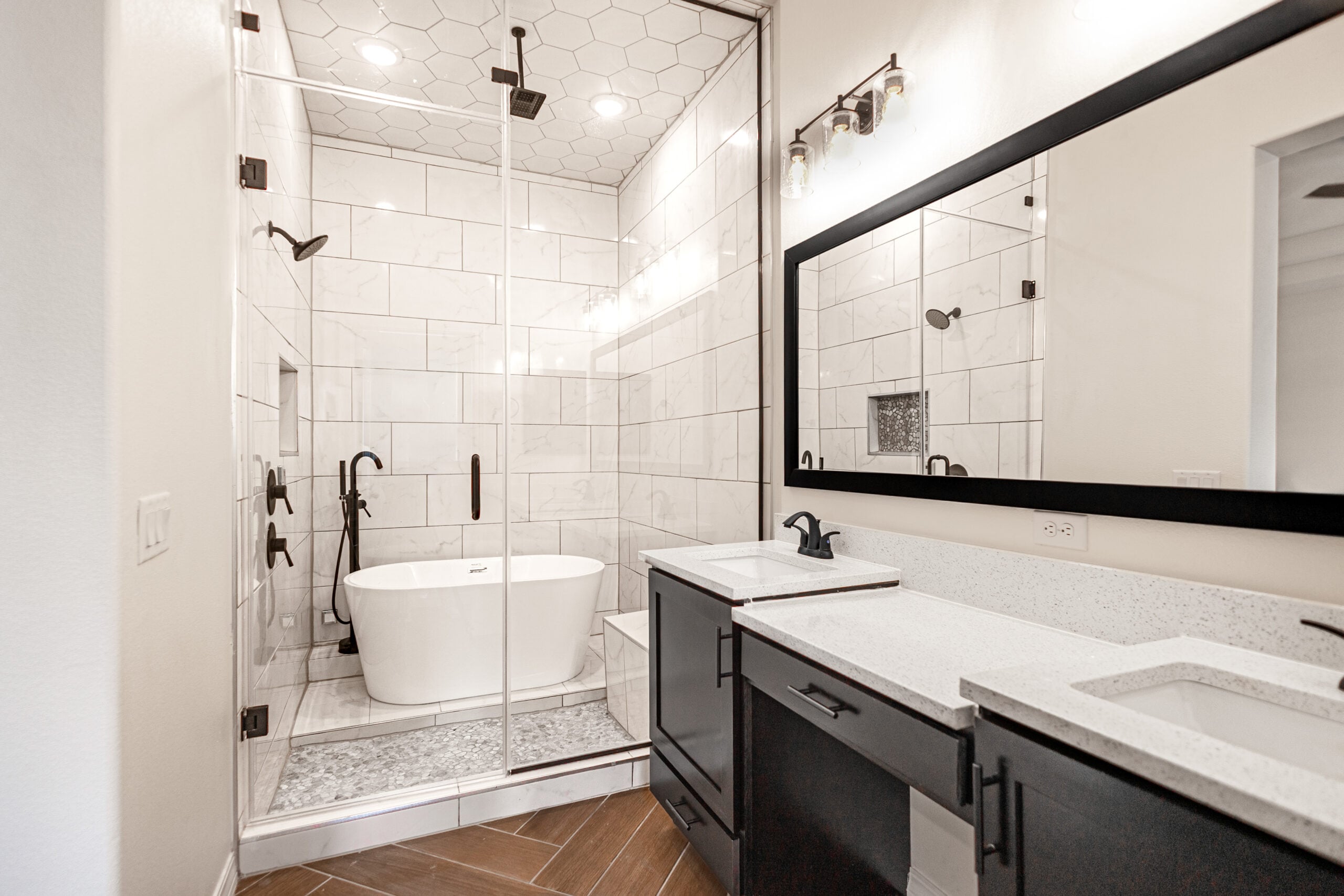 The Daisy Master Bathroom with a large mirror and two sinks. There is a walk-in shower with a free standing tub and sauna.